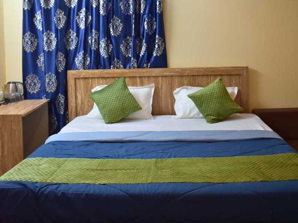 King-size bed with green and blue linen in the Premium Couple Suite at Skandanam Ecoville